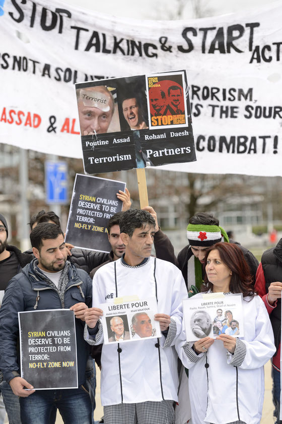 V Ženeve, kde sa začali mierové rokovania o
Sýrii, demonštranti držia transparenty odsudzujúce režim Bašára Asada.