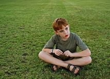 autizmus - dieťa - tráva - smútok - zamyslenie