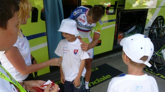 Peter Sagan sa podpisuje na tričko malému...