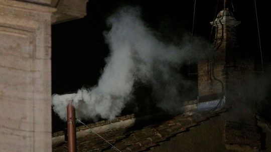 Biely dym stúpa z komína na streche Sixtínskej...