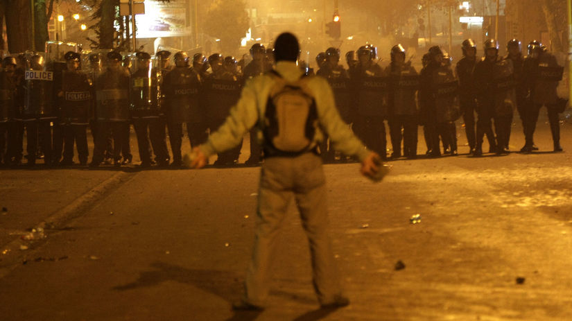 Demonštrant stojí oproti policajnému kordónu v...
