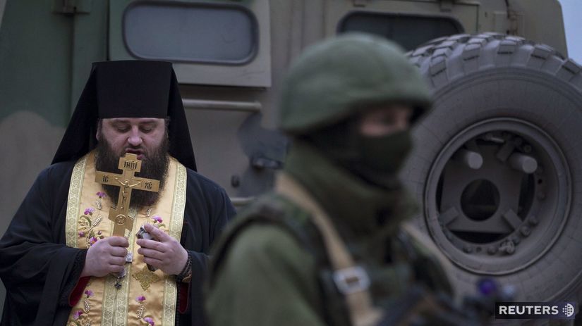 Ortodoxný duchovný sa modlí vedľa vojaka pri...