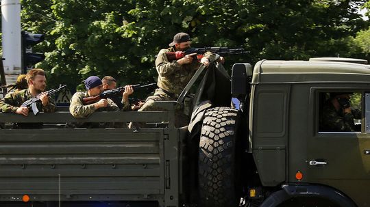 Proruskí ozbrojenci so zbraňami v okolí...