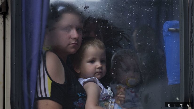 Matka s dieťaťom sa pozerá z okna autobusu pred...