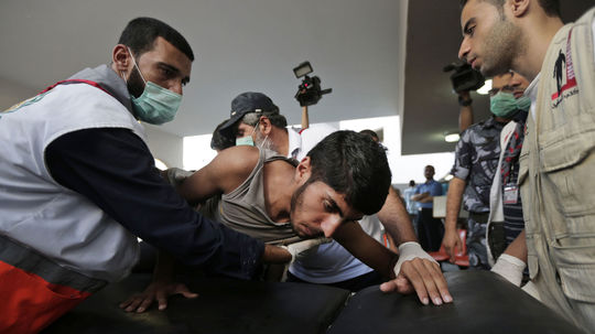 Zdravotníci nesú mladíka, zraneného počas...