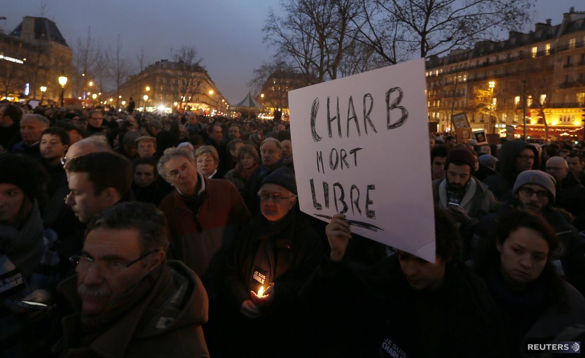 Muž drží transparent, s nápisom "Charb...