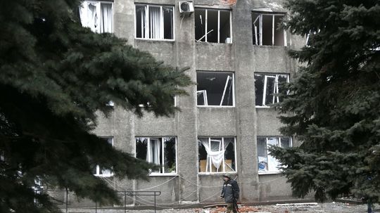 Ukrajinský vojak kráča popri evakuovanom dome v...