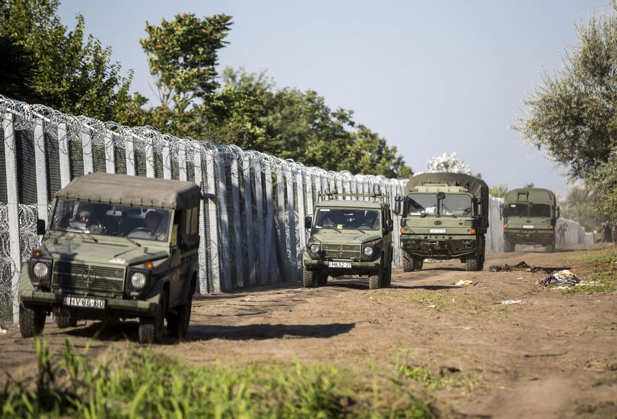 Armádne vozidlá idú pozdĺž plotu na hranici...