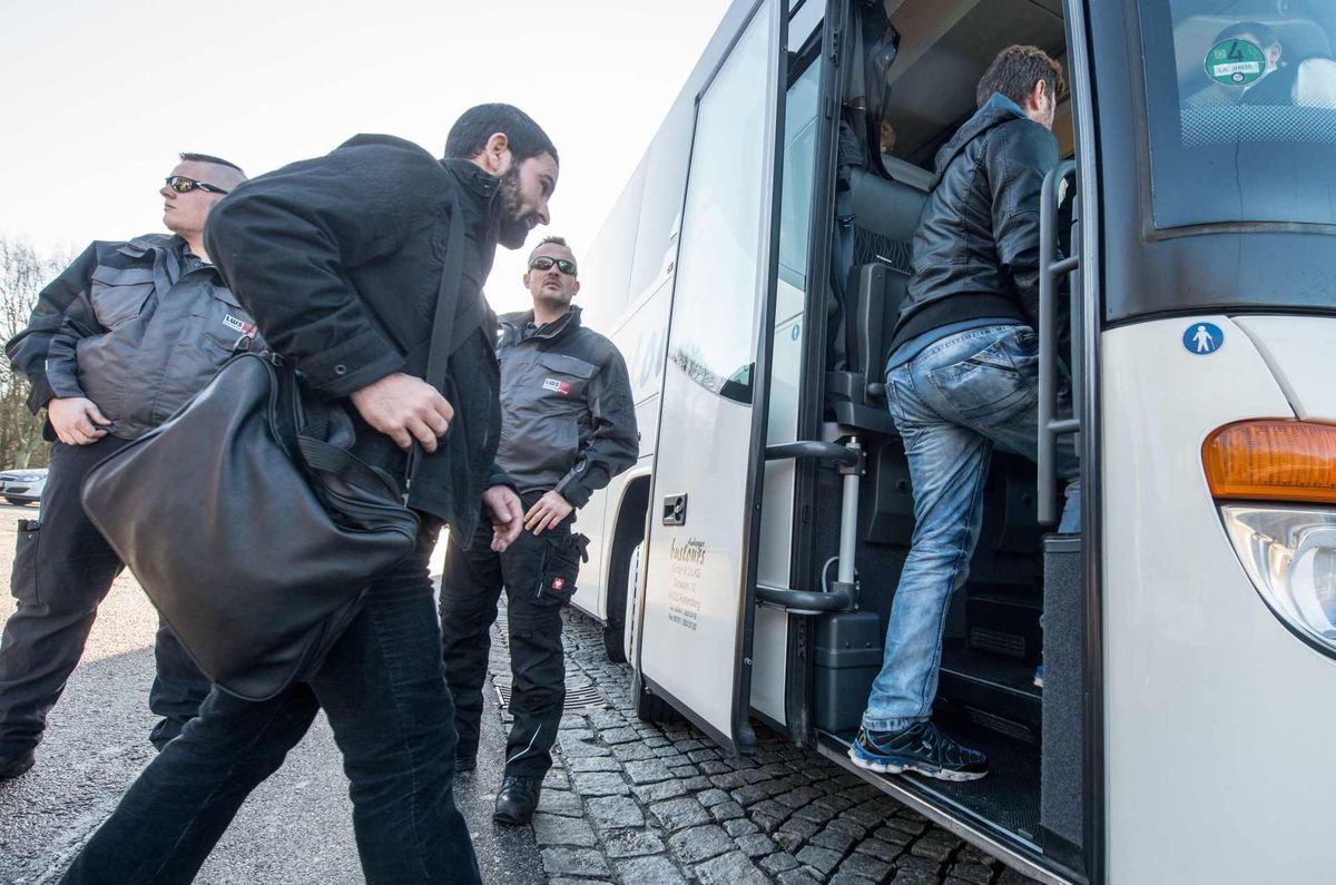 Sýrski utečenci nastupujú do autobusu, ktorý...
