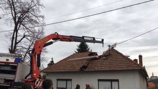 Hasiči sa snažia vytiahnuť vetroň z domu.