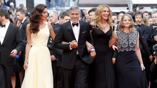 Herec George Clooney s manželkou Amal (vľavo),...