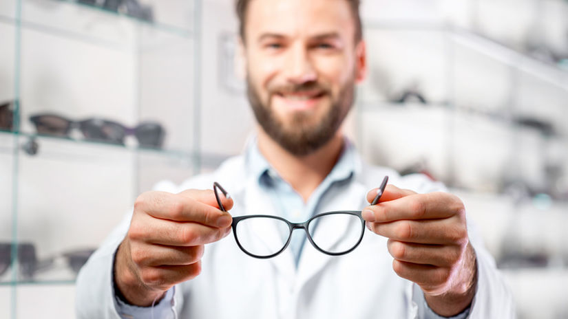 Handsome ophthalmologist holding eyeglasses for...