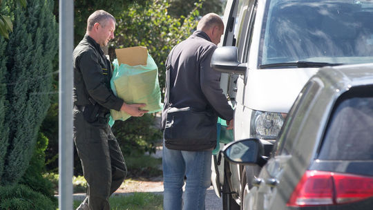 Policajti zaisťujú dôkazy z domu podozrivého.