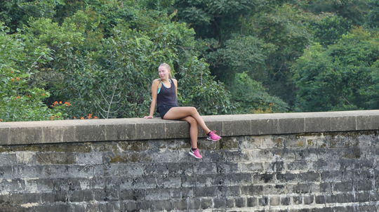 Táto dievčina sedí na múriku mosta, pod ňou je...