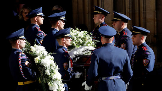 Čestná hradná stráž vynáša rakvu z pozostatkami...