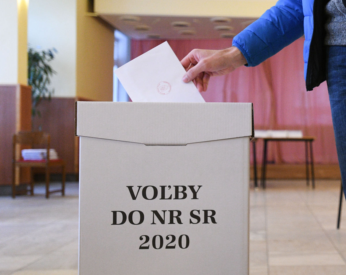 Volič vhadzuje obálku do hlasovacej urny po...