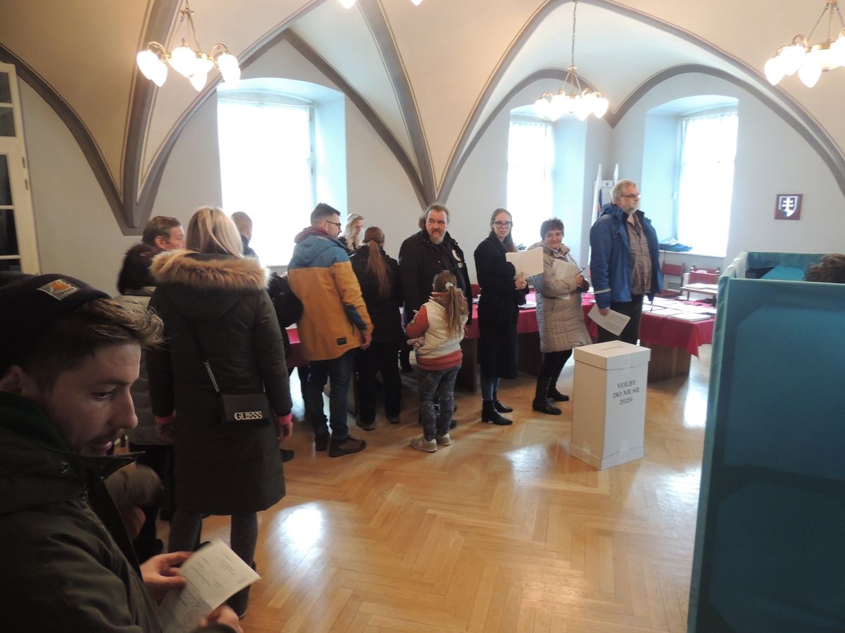 Voliči stoja v rade vo volebnej miestnosti vo...