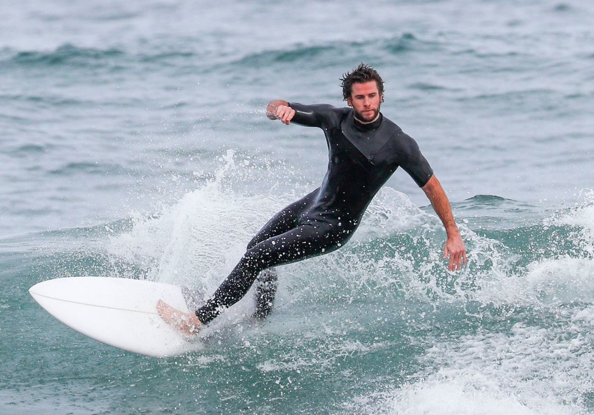 Liam Hemsworth surfuje na pláži na Phillip Island.