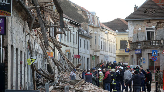 Ľudia prehľadávajú ruiny poškodených budov po...