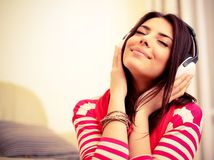 Young beautiful woman in bright outfit enjoying the music at home