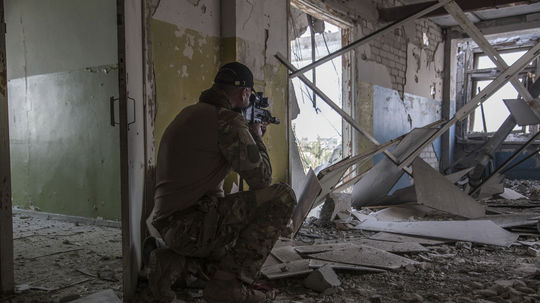 Ukrajinský vojak sa krčí na pozícii počas...