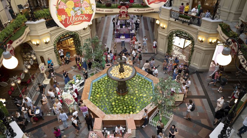 Zákazníci a turisti kráčajú okolo fontány v...