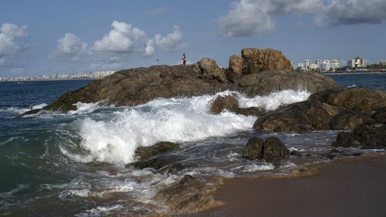 Muž loví ryby zo skál skoro ráno na pláži v...