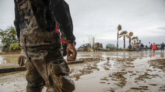 Rescuers work to remove mud after heavy...