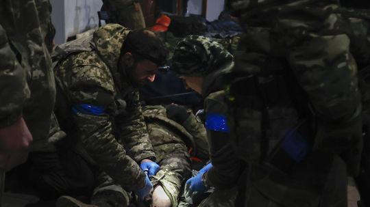 Ukrajinskí vojaci ošetrujú zraneného vojaka v...