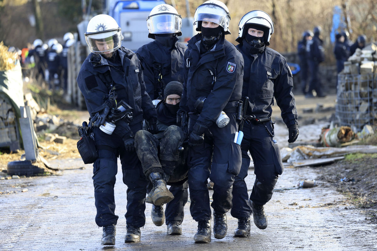 Policajti vynášajú demonštranta z tábora...