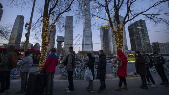 Ľudia s ochrannými rúškami stoja v rade na...