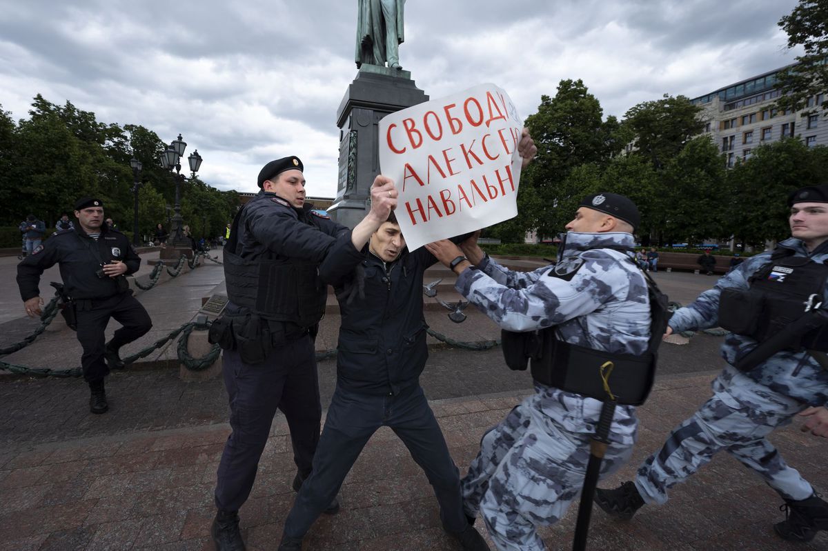 Policajti zatýkajú demonštranta s plagátom, na...