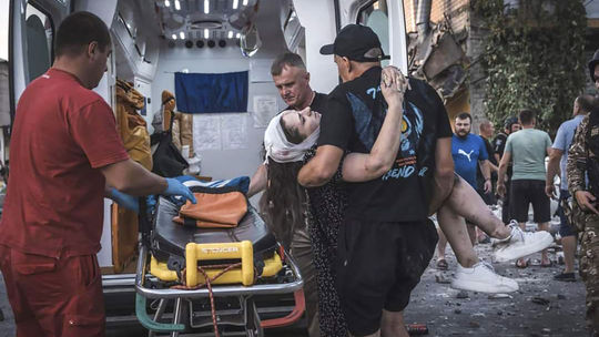 Ukrajinskí záchranári nesú zranenú osobu z...