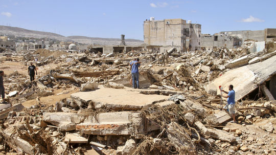 Les gens fouillent les ruines des bâtiments détruits après...