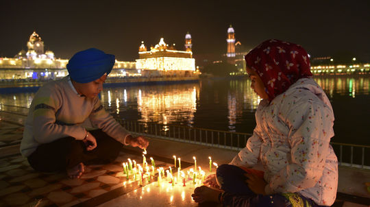 Mladí Sikhovia zapaľujú sviečky v osvetlenom...