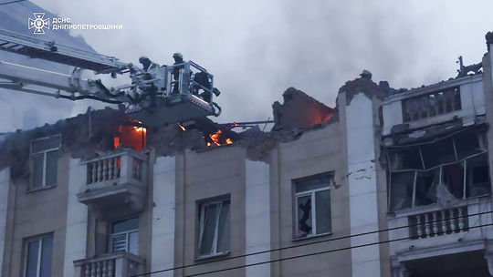 Rescuers extinguish a building hit by a Russian...