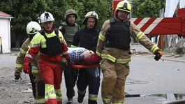 Rescuers carry the injured at the site of the Russian...