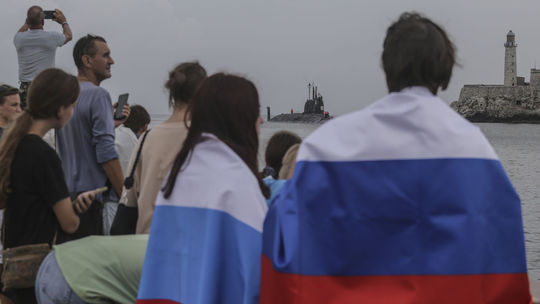 Ľudia odetí v ruských zástavách sledujú ruskú...