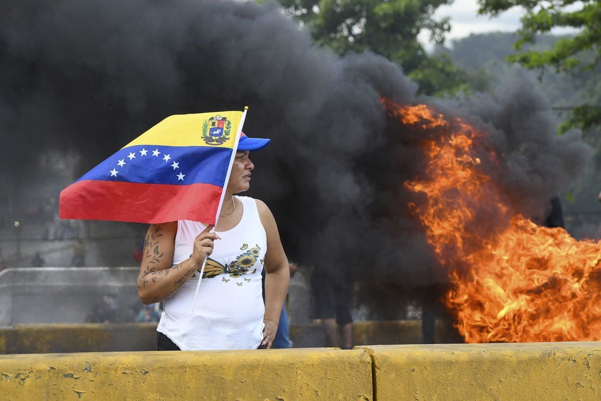 Žena drží venezuelskú vlajku počas protestu...