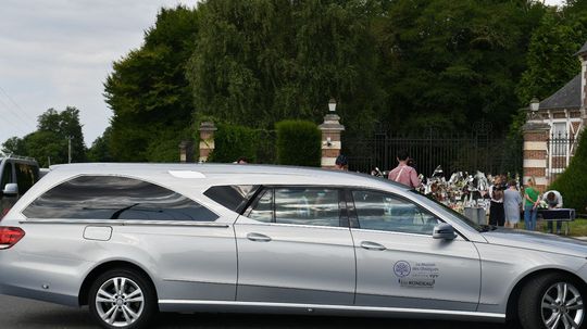 Pohrebný voz s truhlou a pozostatkami Alaina...