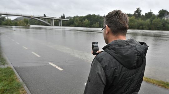 Muž si fotografuje rieku Vltavu rozliatu na...