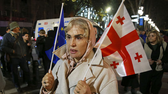 Demonštrantka drží vlajky EÚ a Ukrajiny počas...