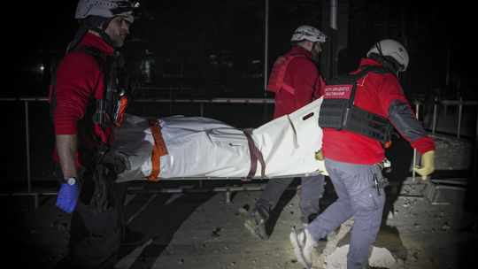Záchranári odnášajú telo civilistu, ktorý...