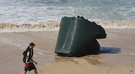 Muž prechádza okolo vodnej nádržky na pláži...