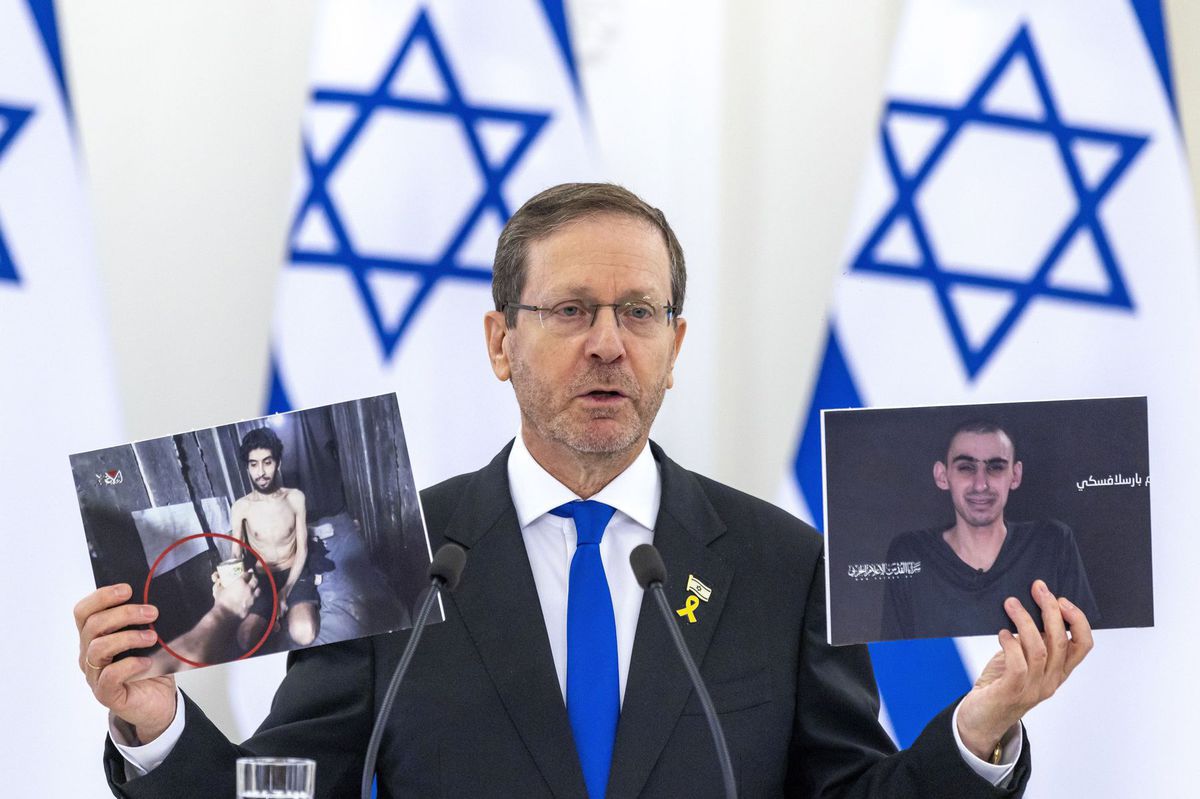 Izraelský prezident Isaac Herzog ukazuje snímky...