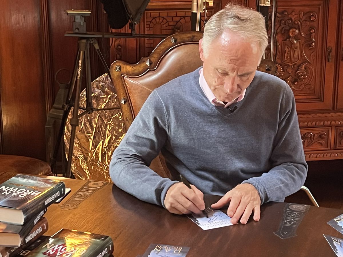 Dan Brown podpisuje kartičky.