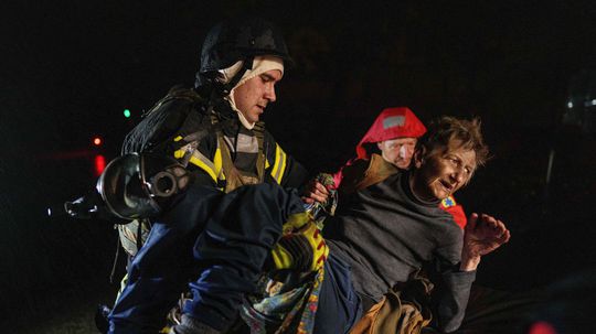 Záchranári nesú zranenú ženu do sanitky po...