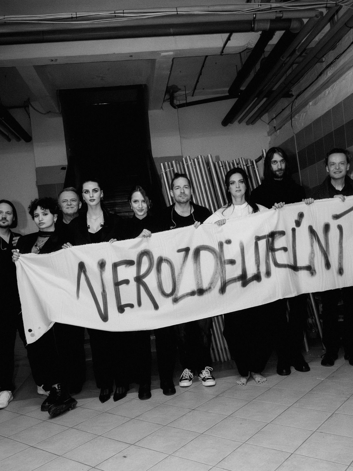 Účastníci koncertu s plátnom s nápisom...