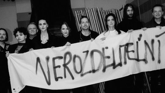 Účastníci koncertu s plátnom s nápisom...