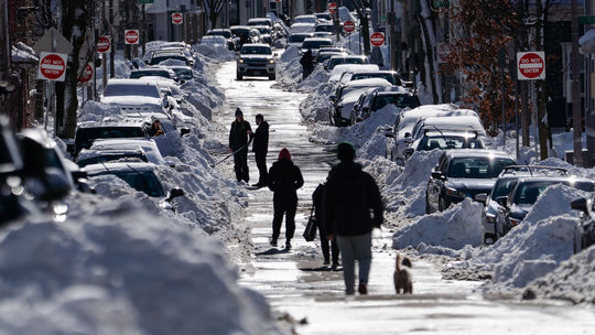 Ľudia kráčajú uprostred ulice po zasnežených...
